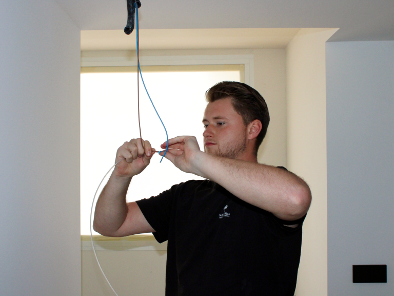 Mallorca Project Support - Deutsche Handwerker auf Mallorca Ein Handwerker verbindet Kabel in einem Raum mit einem Fenster im Hintergrund.